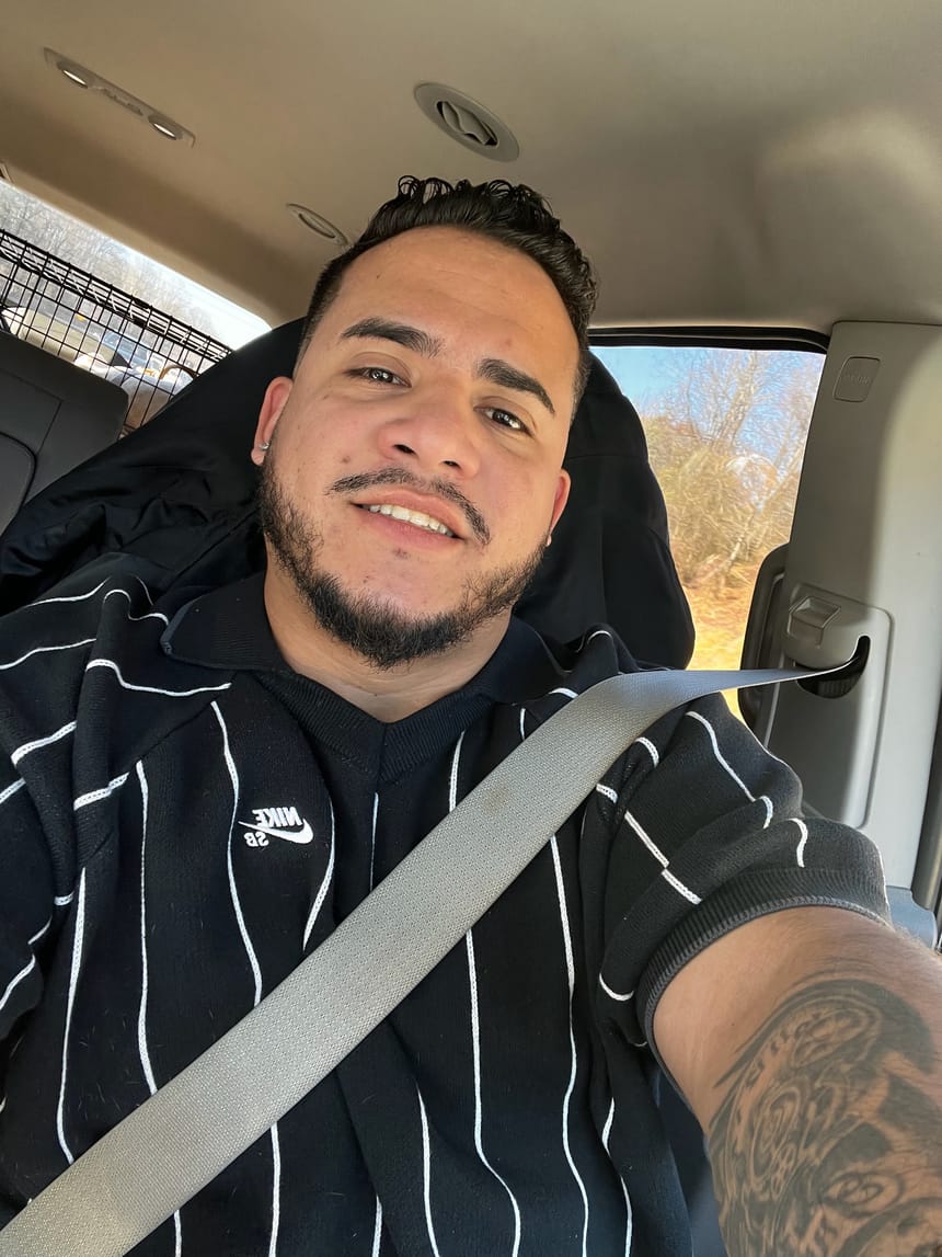 Selfie sonriente de Cristian en el coche con suéter negro de rayas